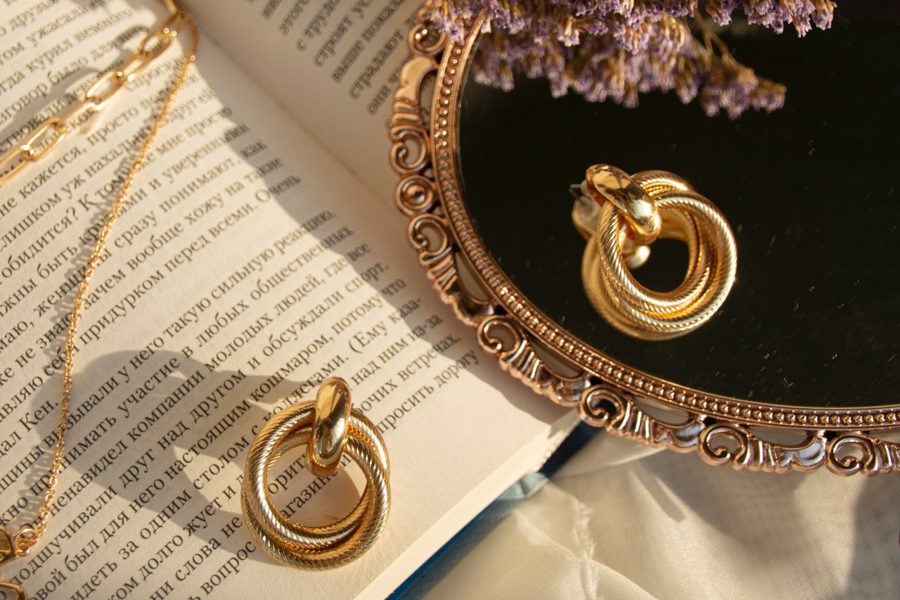 gold earrings resting on a mirror and a book