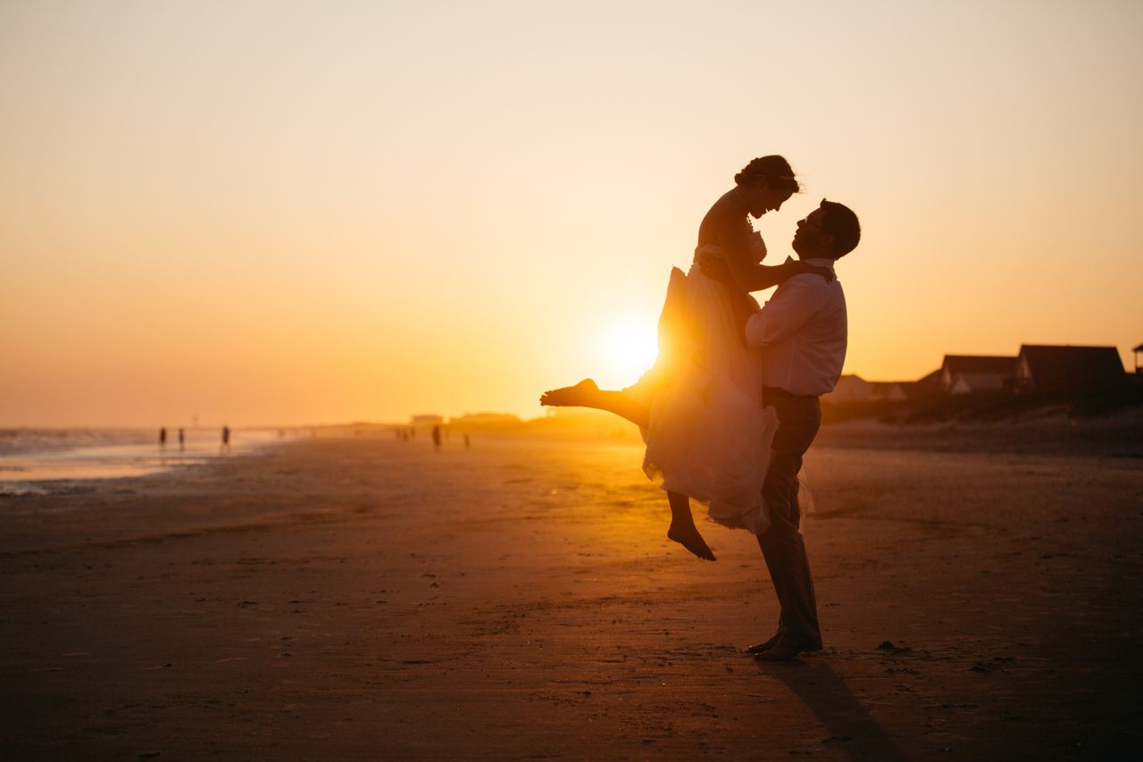 A couple embraces as the sun sets on a beach