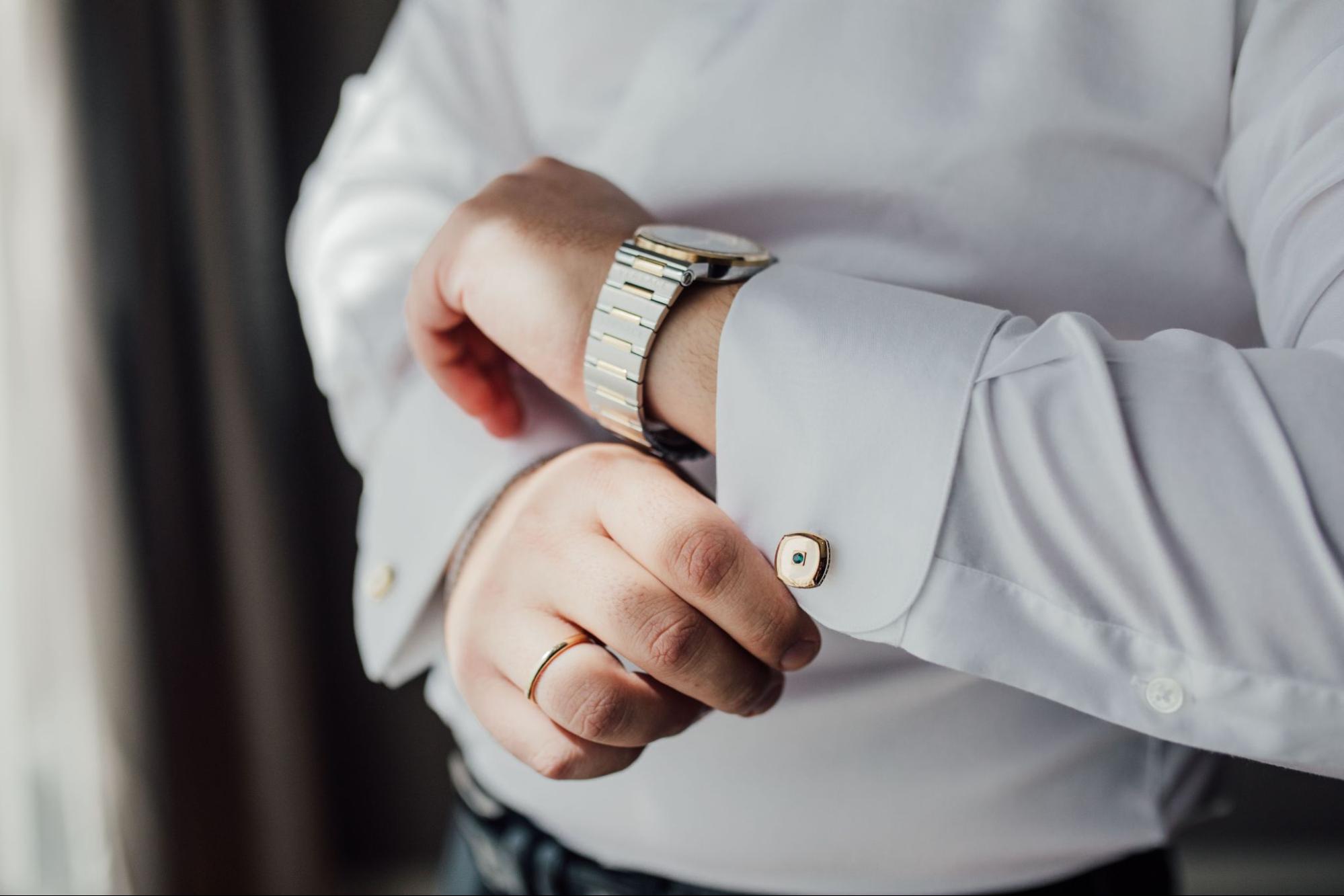 A man in a white shirt wearing a mixed-metal wristwatch.