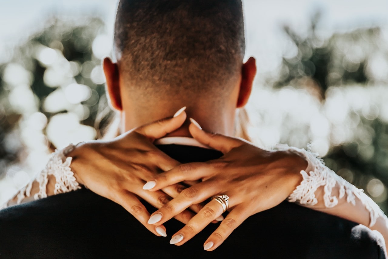 A woman dances with her new husband while wearing a silver solitaire engagement ring and channel-set wedding band