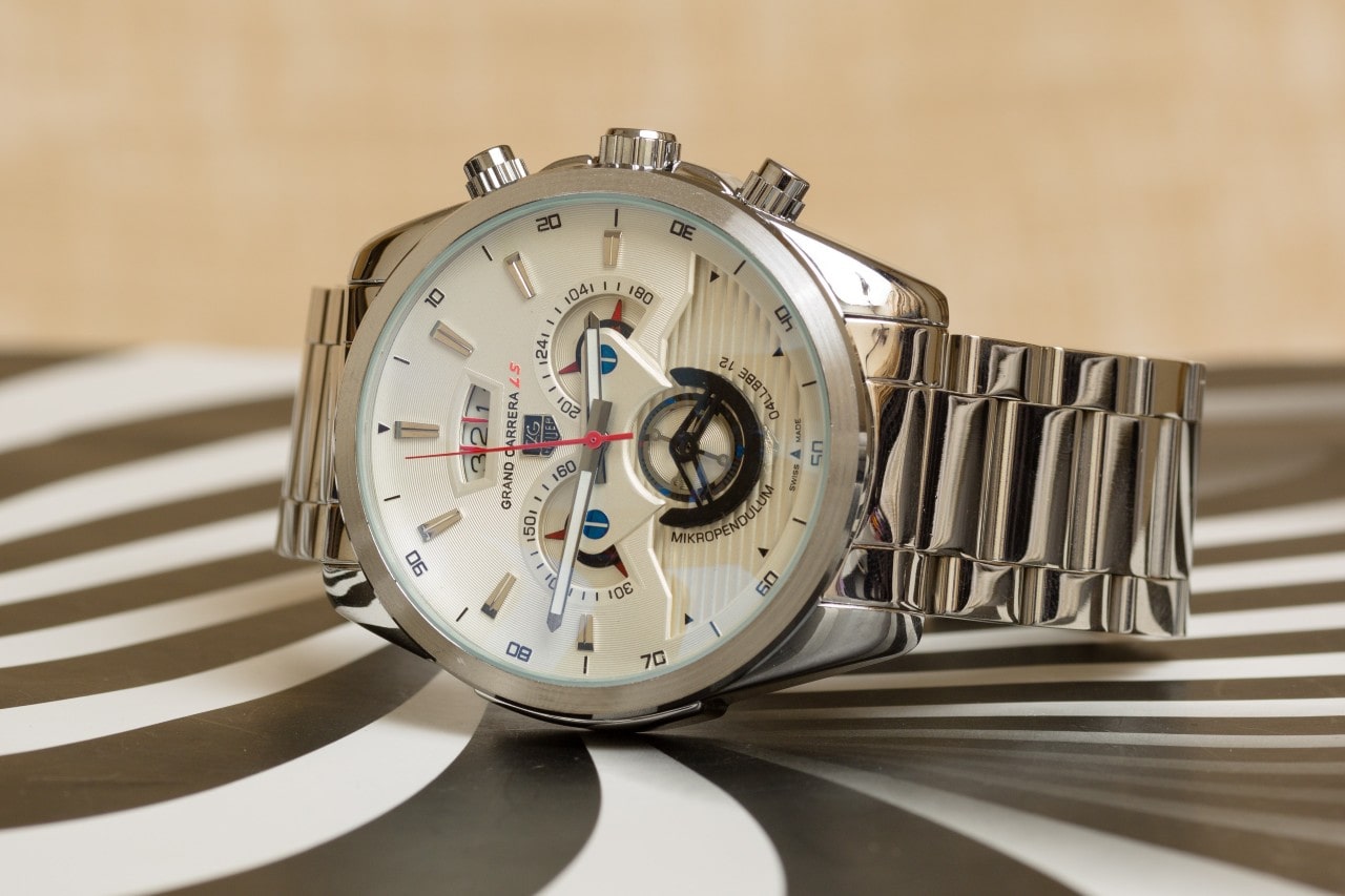 A TAG Heuer watch with a white dial and stainless steel bracelet on a black and white surface.