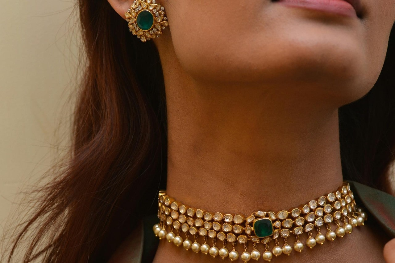 a woman wearing a matching green gemstone and diamond necklace and earring set