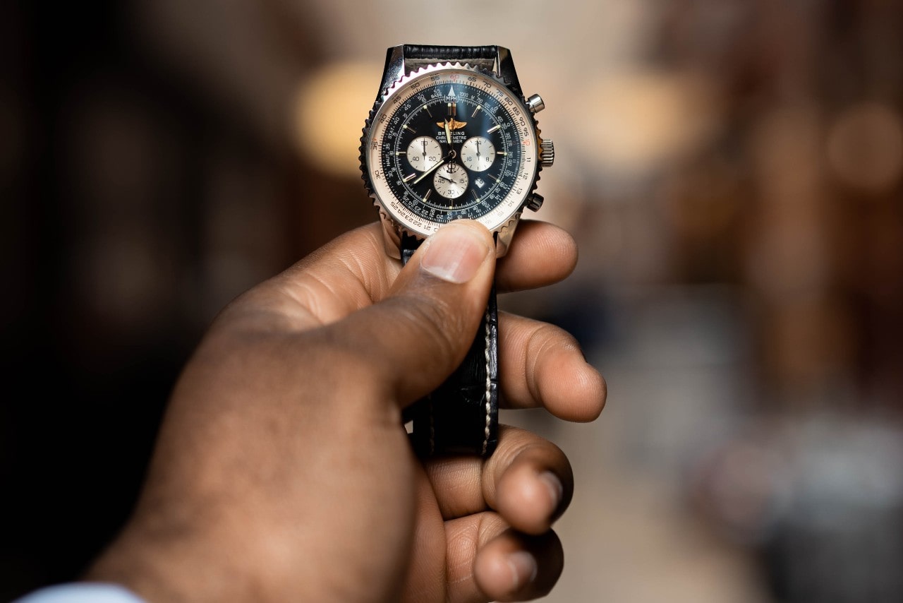 A man holds up his favorite Breitling timepiece to check the time at a dinner party