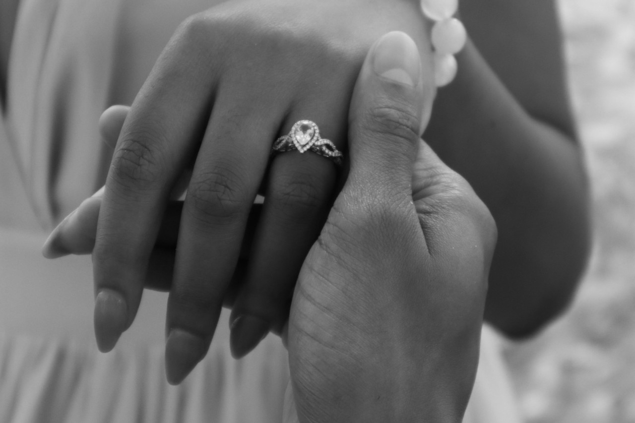 A pear shaped center stone with halo and interweaving band