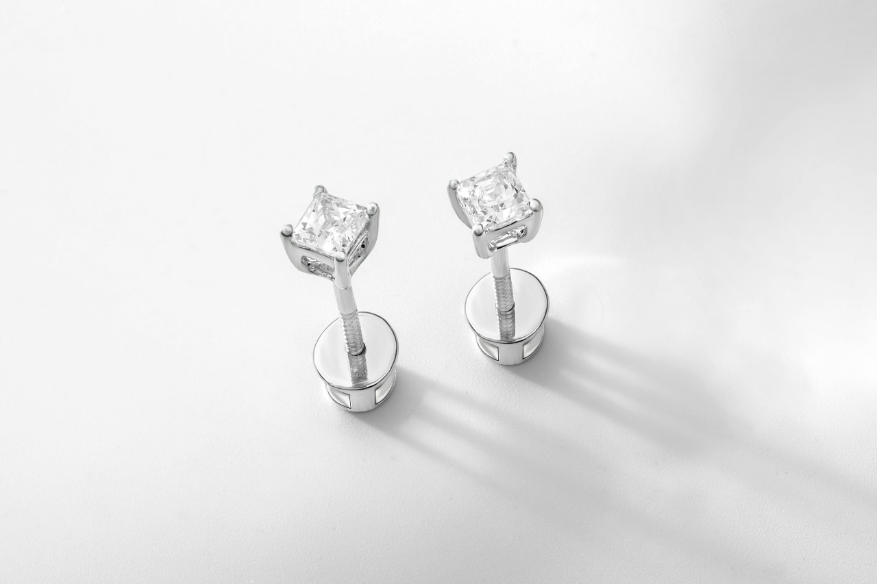 A top-down view of a pair of white gold diamond studs on a white backdrop.